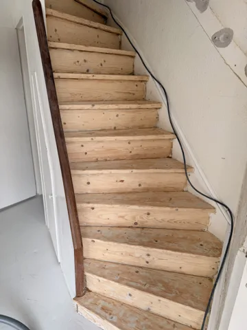 Houten trap met draaiing en zwarte leuning